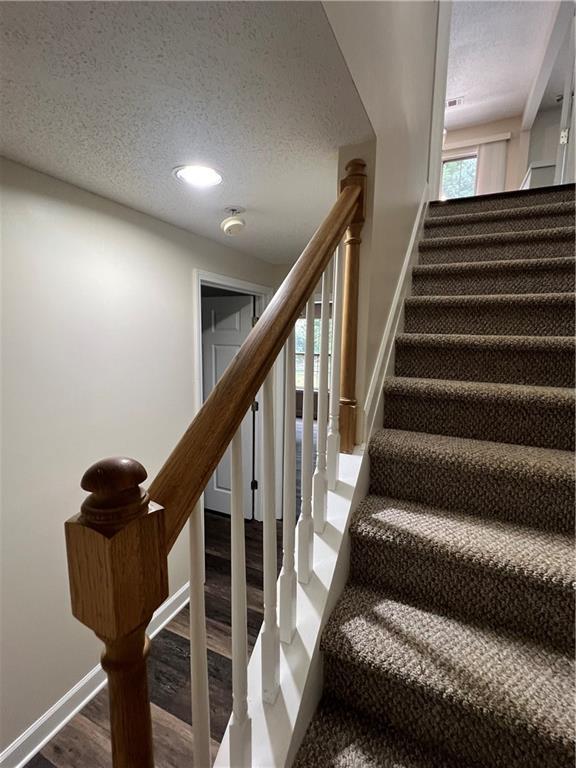 11800 Carriage Park Ln, Johns Creek, GA 30097 - stairway featuring a textured ceiling, wood finished floors, and recessed lighting
