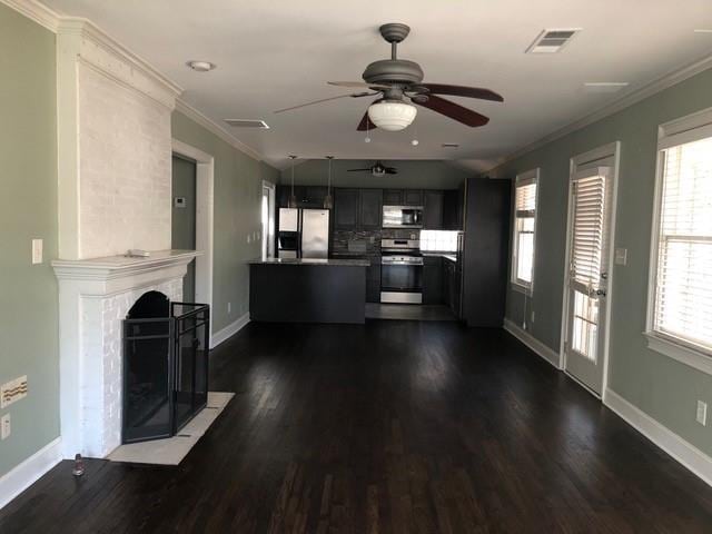 unfurnished living room featuring a fireplace with flush hearth, visible vents, baseboards, ornamental molding, and dark wood finished floors