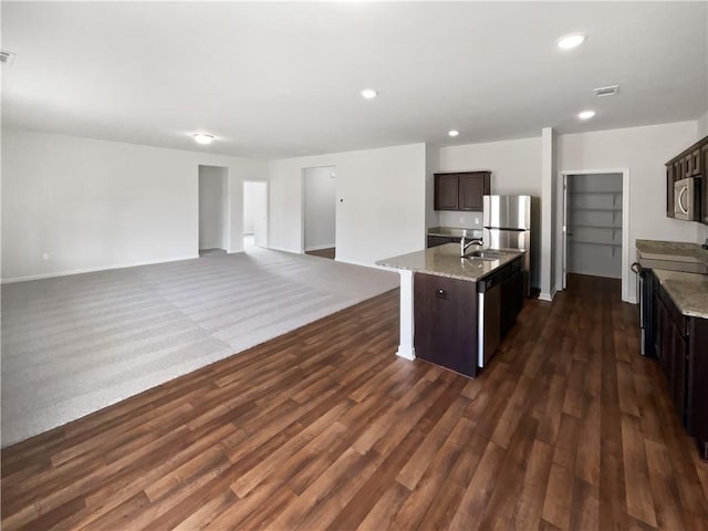 kitchen with a center island with sink, visible vents, appliances with stainless steel finishes, a sink, and dark brown cabinets