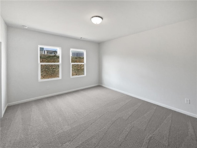 empty room featuring baseboards and dark carpet