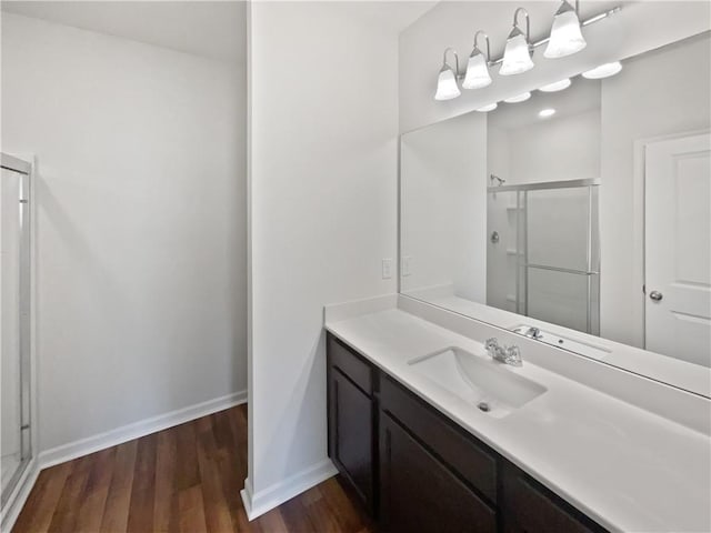 full bathroom featuring vanity, a shower stall, baseboards, and wood finished floors