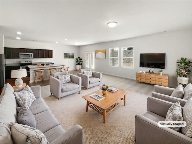 living room with light wood-style flooring, baseboards, and recessed lighting