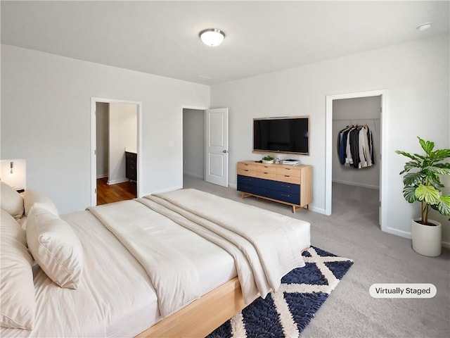 bedroom with light carpet, baseboards, a walk in closet, and a closet