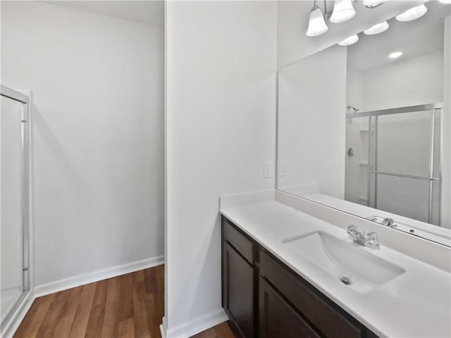 full bath featuring a stall shower, wood finished floors, vanity, and baseboards