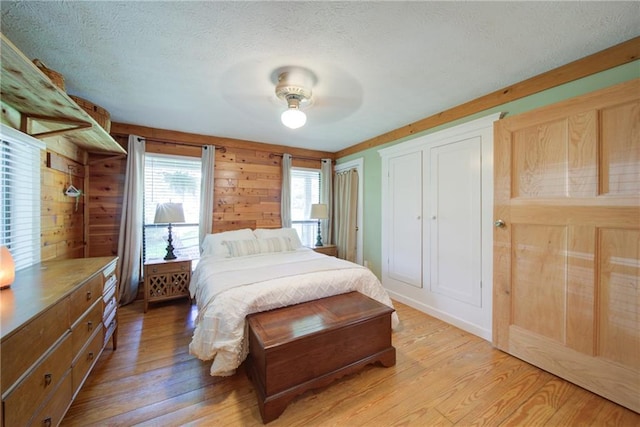 1066 Sea Oats Way SW, Lilburn, GA 30047 - bedroom featuring light wood-style flooring, a textured ceiling, wood walls, and a ceiling fan