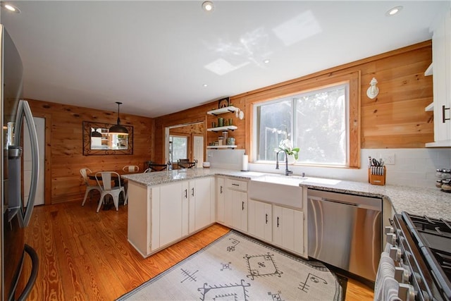 1066 Sea Oats Way SW, Lilburn, GA 30047 - kitchen with stainless steel appliances, wood walls, light wood-style flooring, a peninsula, and white cabinetry