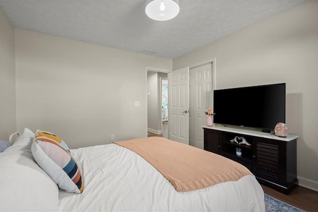 bedroom featuring dark wood-style flooring, a textured ceiling, and baseboards