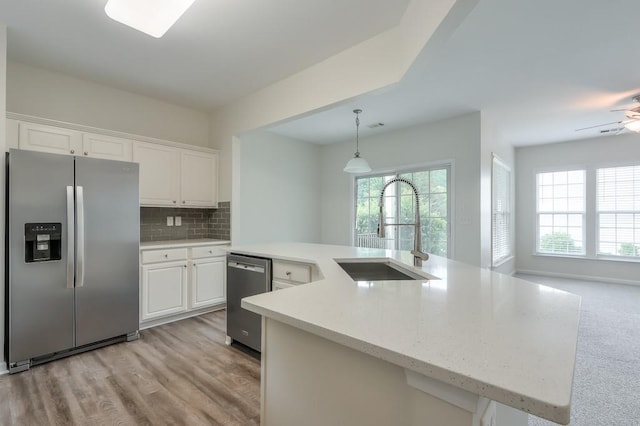 502 Helene Ct, Woodstock, GA 30188 - kitchen with appliances with stainless steel finishes, a sink, white cabinetry, decorative backsplash, and pendant lighting