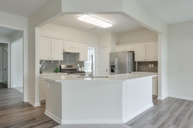 502 Helene Ct, Woodstock, GA 30188 - kitchen with stainless steel appliances, decorative backsplash, a kitchen island with sink, light countertops, and wood finished floors
