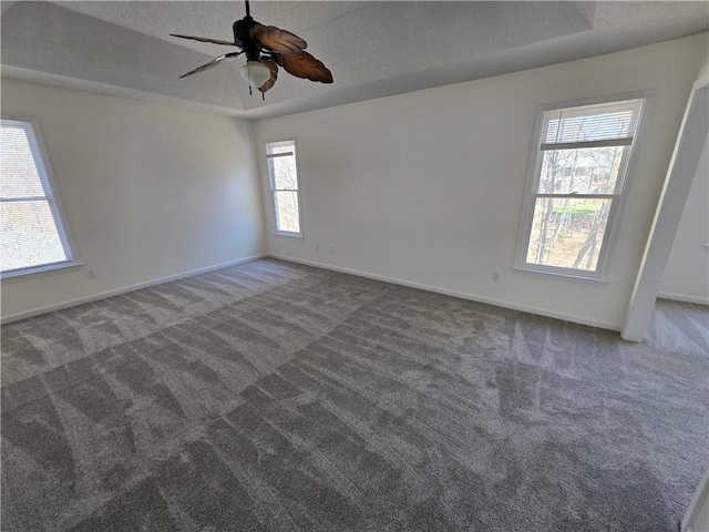 spare room featuring a textured ceiling, ceiling fan, carpet flooring, baseboards, and a tray ceiling