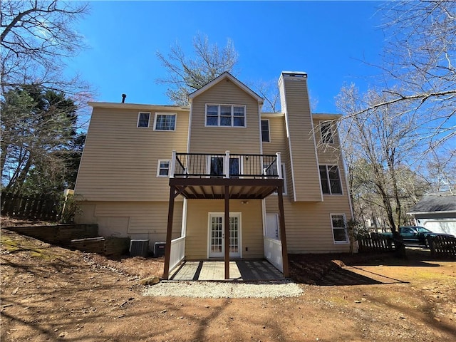 rear view of house with a deck, a patio, central AC unit, french doors, and a chimney