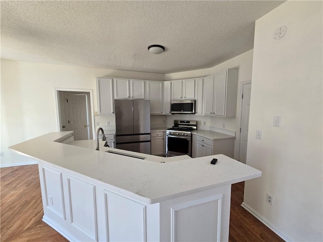 kitchen featuring a spacious island, light wood-style flooring, stainless steel appliances, a textured ceiling, and a sink