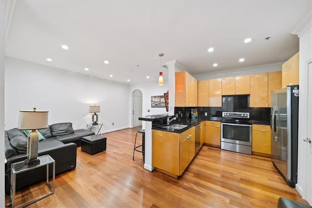 kitchen featuring appliances with stainless steel finishes, a breakfast bar, sink, light hardwood / wood-style floors, and kitchen peninsula