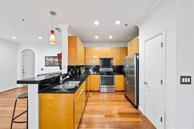 kitchen with appliances with stainless steel finishes, pendant lighting, a breakfast bar area, kitchen peninsula, and light wood-type flooring