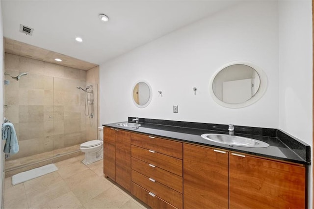 bathroom with vanity, tile patterned floors, toilet, and a tile shower