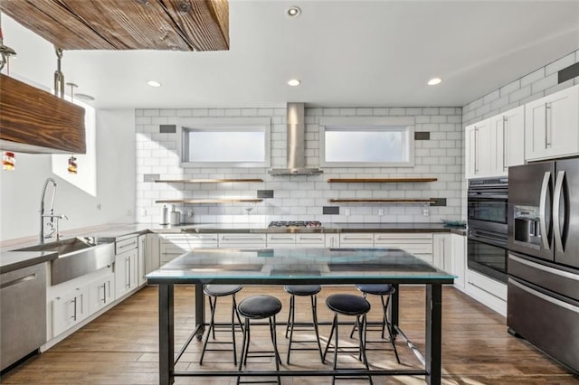 kitchen with black appliances, wall chimney exhaust hood, open shelves, and a sink