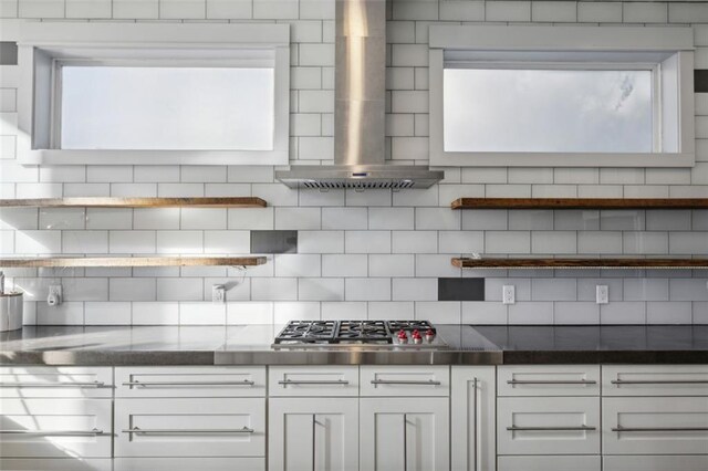 kitchen with white cabinetry, tasteful backsplash, stainless steel gas cooktop, stainless steel counters, and wall chimney exhaust hood