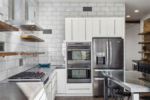 kitchen featuring wall chimney range hood, stainless steel appliances, white cabinetry, and open shelves