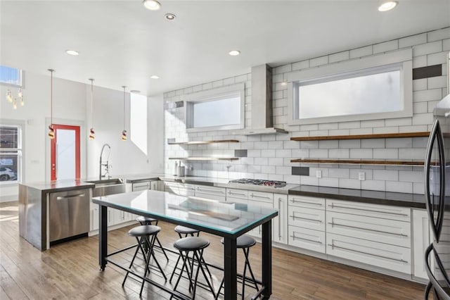 kitchen with a peninsula, dark wood-style flooring, white cabinetry, appliances with stainless steel finishes, and backsplash