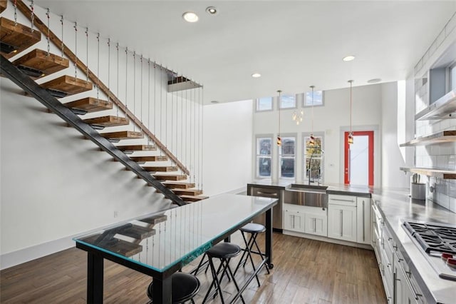 kitchen featuring open shelves, hardwood / wood-style floors, a sink, white cabinets, and a peninsula