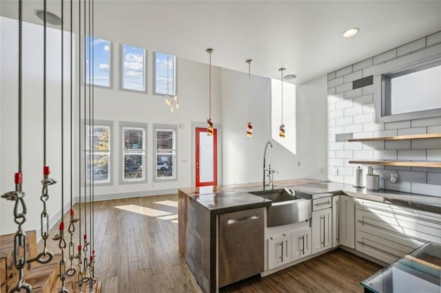 kitchen with a sink, dark wood-style floors, decorative backsplash, and dishwasher