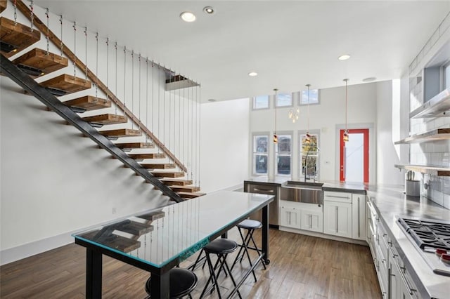 kitchen featuring hardwood / wood-style flooring, a peninsula, a sink, white cabinets, and open shelves