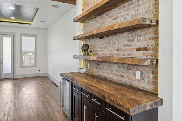 bar featuring wine cooler, wood-type flooring, and baseboards