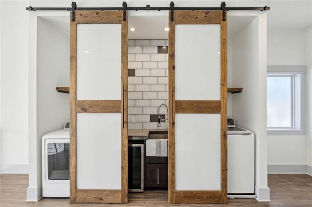 interior space with a barn door, washer / clothes dryer, wood finished floors, and beverage cooler