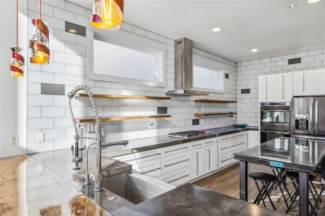 kitchen with open shelves, dobule oven black, wall chimney exhaust hood, stainless steel gas stovetop, and dark countertops