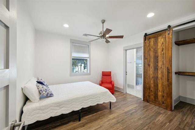 bedroom with a barn door, wood finished floors, and recessed lighting