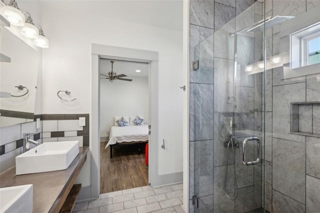 ensuite bathroom featuring double vanity, a stall shower, connected bathroom, a sink, and ceiling fan