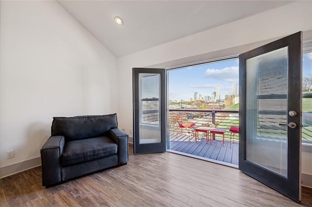 sitting room featuring baseboards, wood finished floors, recessed lighting, a view of city, and vaulted ceiling
