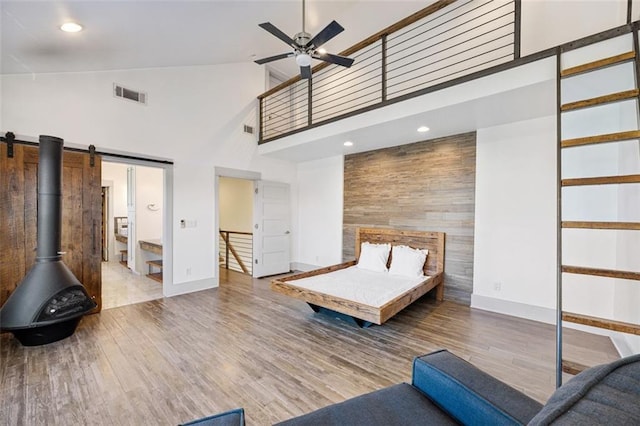 unfurnished bedroom featuring baseboards, visible vents, wood finished floors, and a towering ceiling