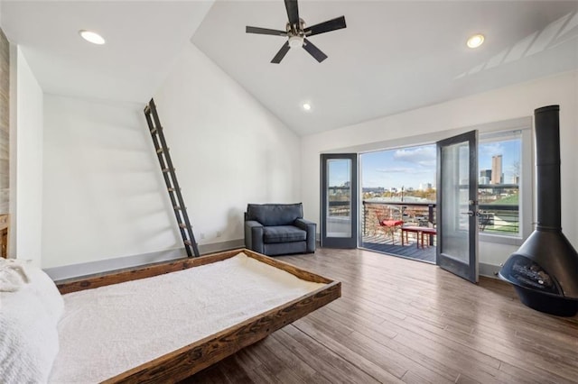 sitting room featuring a city view, recessed lighting, a wood stove, vaulted ceiling, and wood finished floors