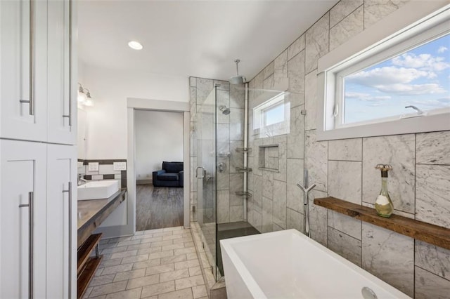 bathroom with vanity, a soaking tub, a shower stall, and tile walls