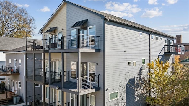 view of side of home with central AC unit and a balcony