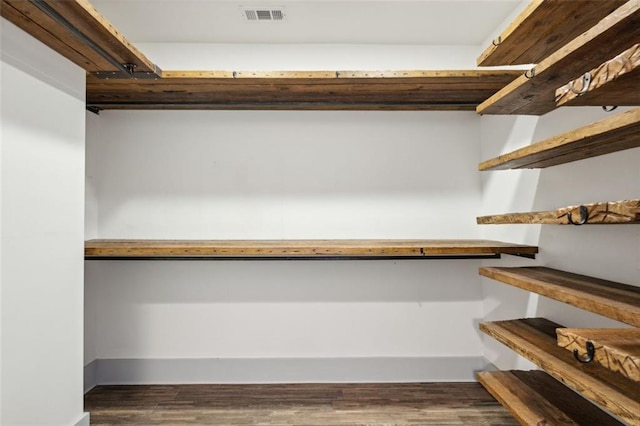 walk in closet with visible vents and dark wood finished floors