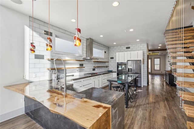 kitchen with wall chimney exhaust hood, stainless steel appliances, backsplash, and dark wood finished floors