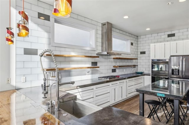 kitchen with open shelves, dark countertops, dobule oven black, stainless steel gas stovetop, and wall chimney exhaust hood