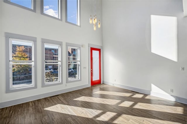 entrance foyer with a towering ceiling, baseboards, a chandelier, and wood finished floors