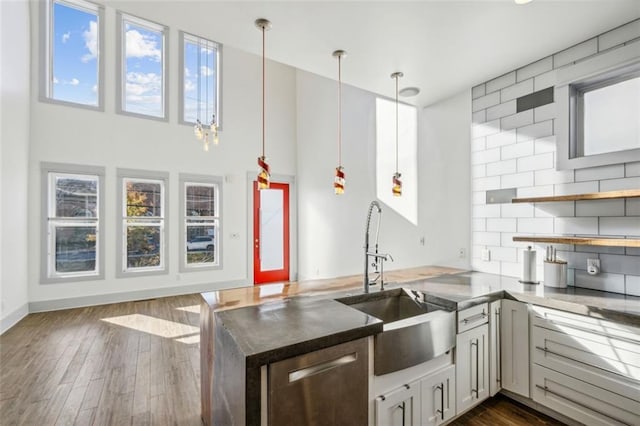 kitchen featuring a peninsula, a sink, decorative backsplash, dark countertops, and dark wood finished floors