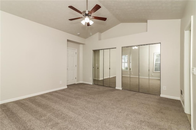 unfurnished bedroom with vaulted ceiling, a ceiling fan, multiple closets, carpet floors, and baseboards