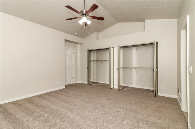 unfurnished bedroom featuring multiple closets, vaulted ceiling, carpet floors, baseboards, and a textured ceiling