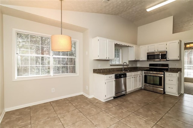 kitchen featuring tile patterned flooring, lofted ceiling, appliances with stainless steel finishes, and white cabinets
