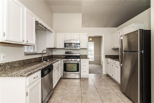 kitchen with white cabinets, a sink, dark stone countertops, and appliances with stainless steel finishes