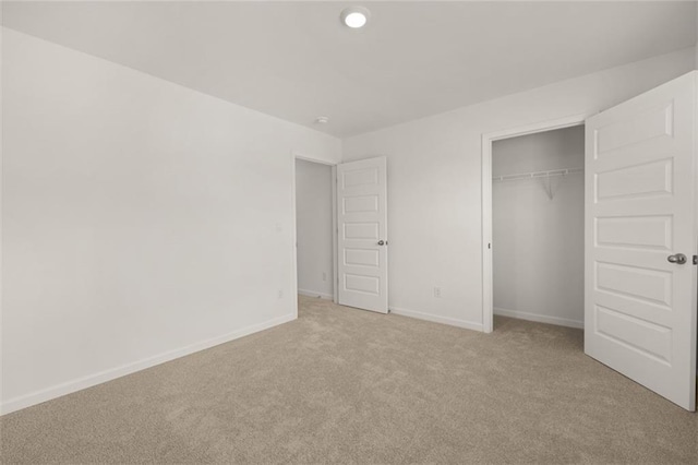 unfurnished bedroom with light colored carpet and a closet