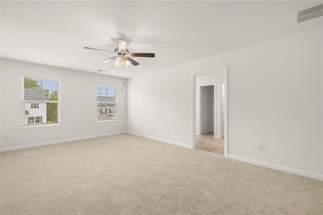 empty room featuring ceiling fan and light carpet