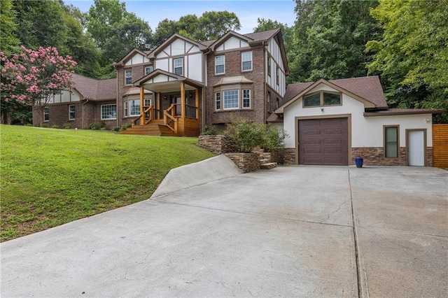 tudor home featuring driveway, a front lawn, an attached garage, and stucco siding