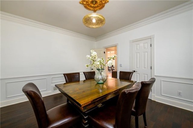 dining room featuring dark wood-type flooring, a wainscoted wall, ornamental molding, and a decorative wall