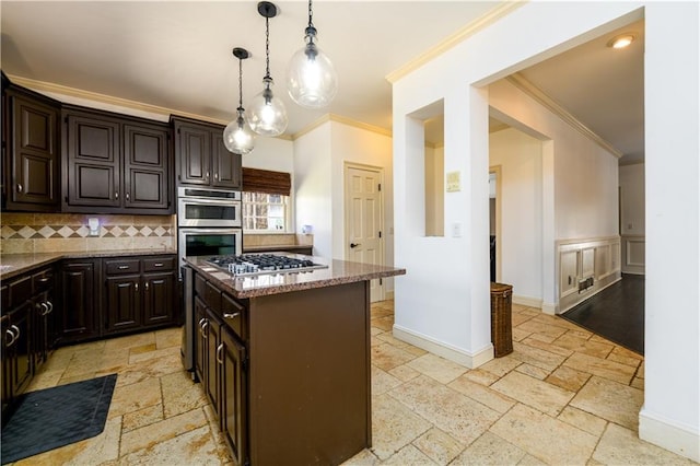 kitchen with a center island, ornamental molding, dark stone countertops, stone tile flooring, and stainless steel appliances